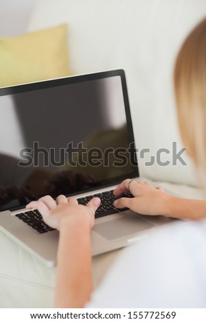 Blonde woman typing on laptop sitting on floor