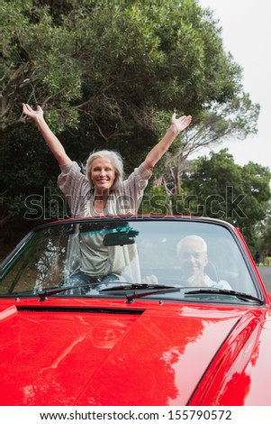 Smiling mature couple having a ride together in red convertible