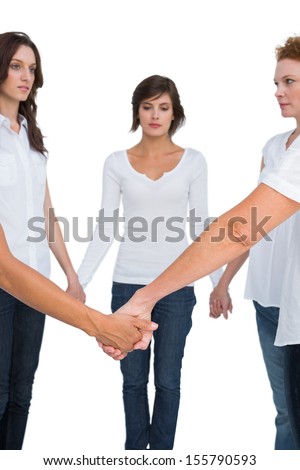 Pensive women standing and holding hands in a circle on white background