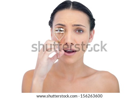 Astonished natural brunette with eyelash curler on white background