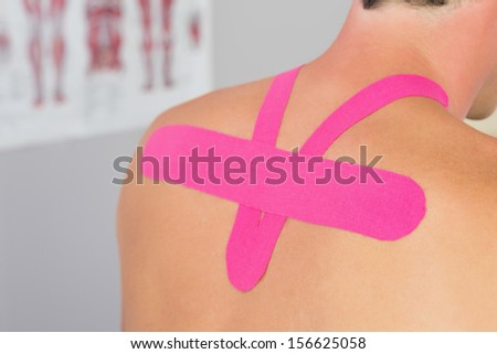 Close up of male patients back with applied pink kinesio tape in bright office