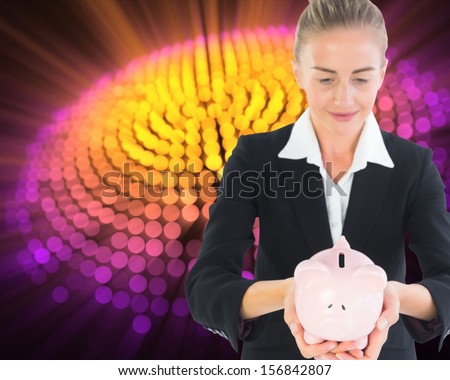 Composite image of blonde businesswoman holding piggy bank in front of glowing circle on black background