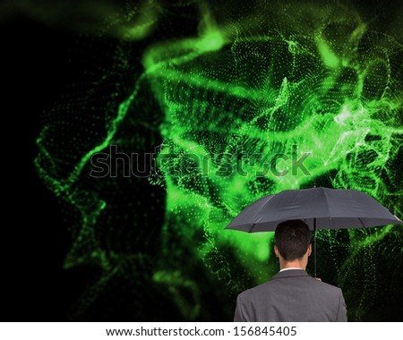 Composite image of rear view of businessman holding grey umbrella on black background with green glowing pattern