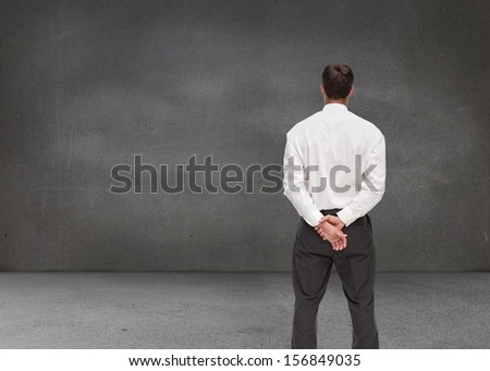 Composite image of businessman turning his back to camera in grey room