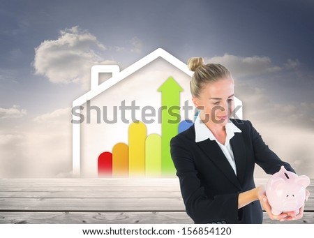 Composite image of blonde businesswoman holding piggy bank in front of house containing statistic