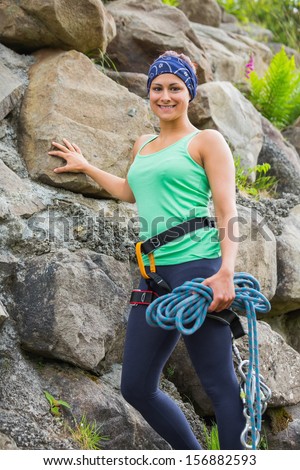 Attractive female rock climber smiling at camera leaning on rock face