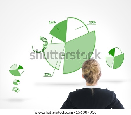 Composite image of businesswoman standing with hands on hips watching green diagrams on white background