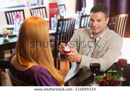 Handsome man proposing marriage to his pretty girlfriend in a classy restaurant