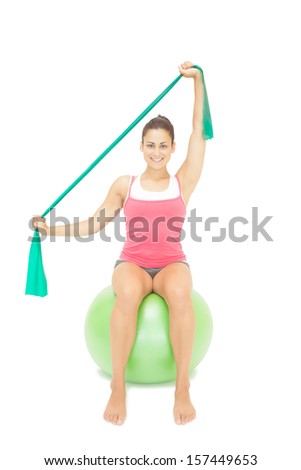Cheery sporty brunette stretching with resistance band on white background