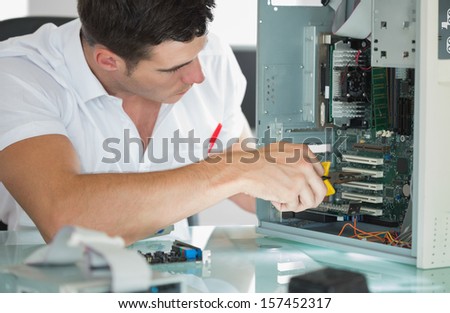 Handsome computer engineer repairing computer with pliers in bright office