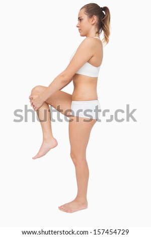Cute pony tailed woman stretching her legs on white background