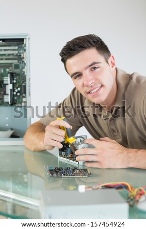 Handsome cheerful computer engineer repairing hardware with pliers in bright office