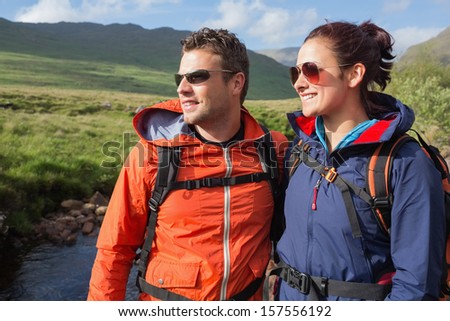 Couple wearing rain jackets and sunglasses admiring the scenery in the countryside