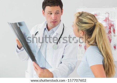 Concerned doctor showing a patient something on x-ray in bright office