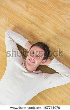 Casual smiling man lying on floor looking at camera in bright room