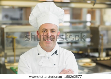 Mature head chef posing with crossed arms standing in a professional kitchen