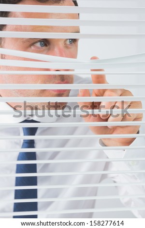 Nice looking businessman spying through roller blind