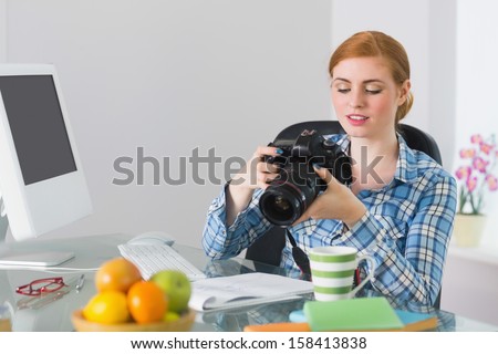 Thoughtful photographer sitting at her desk looking at camera working from home