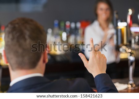 Handsome man ordering a drink from pretty waitress in a classy bar