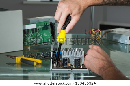 Hands repairing hardware with screw driver in bright office