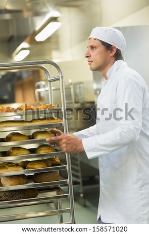 Handsome young baker pushing a trolley with food on it