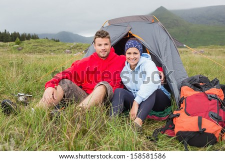 Couple on camping trip smiling at camera outside their tent