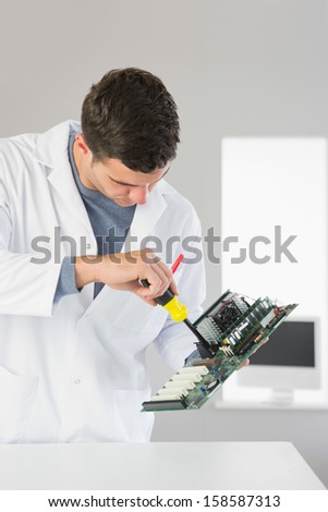 Attractive computer engineer repairing hardware with screw driver in bright office