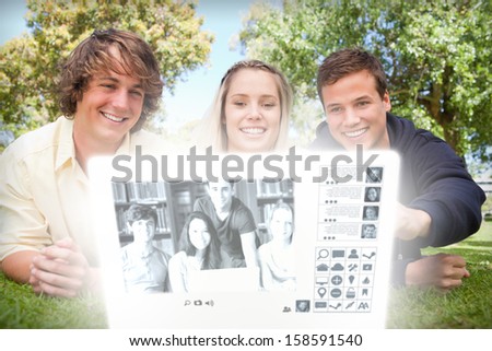 Smiling college friends watching photos together on digital interface in bright park