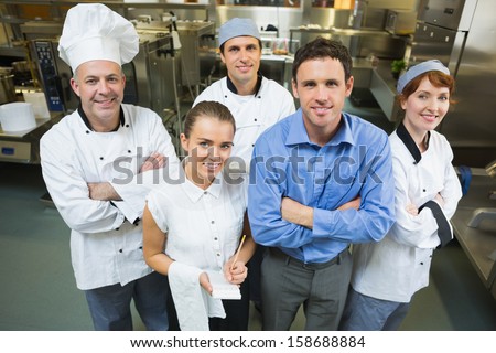 Handsome manager posing with some chefs and waitress in a kitchen