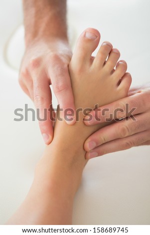 Physiotherapist kneading patients foot in bright office