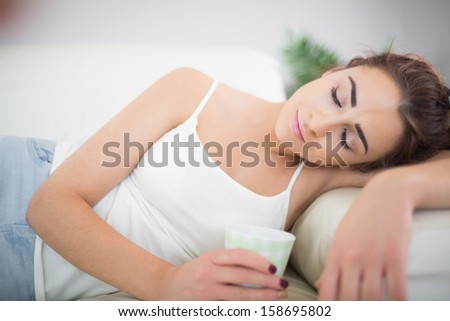Beautiful exhausted woman holding a cup with closed eyes