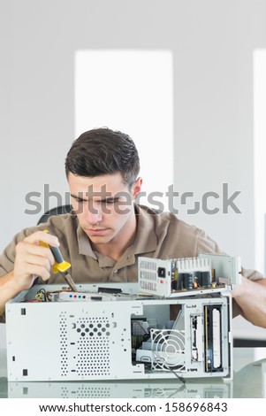 Handsome serious computer engineer repairing open computer in bright office