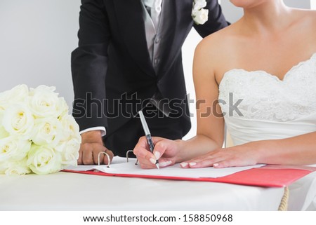 Mid section of a young couple signing wedding contract sitting at desk
