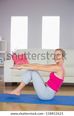 Sporty happy blonde doing core exercise in bright living room