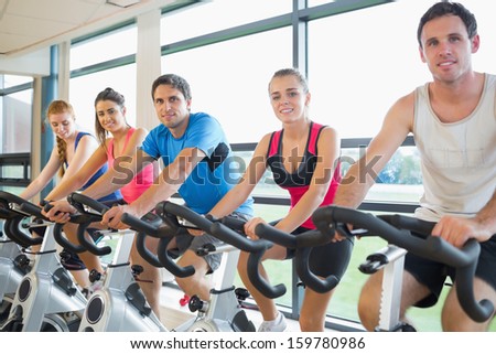 Portrait of five people working out at a stationary bicycle class in the gym