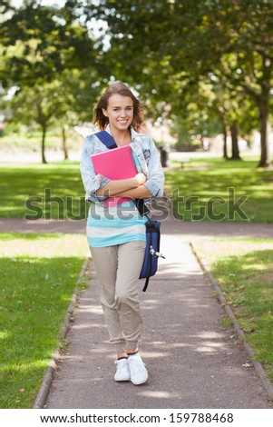 Pretty happy student carrying notebook on campus at college
