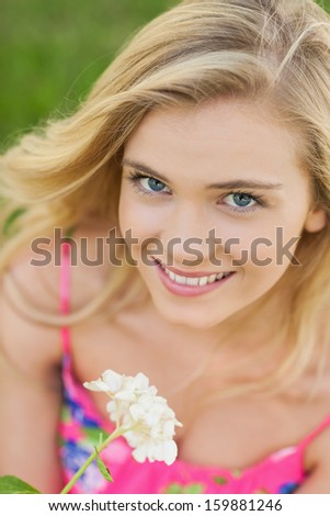 Portrait of lovely woman holding a white flower smiling at camera