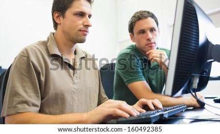 Concentrated teacher and mature student using computer in the computer room