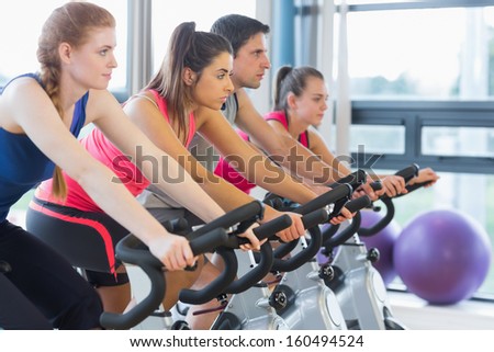 Side view of four people working out on exercise bikes