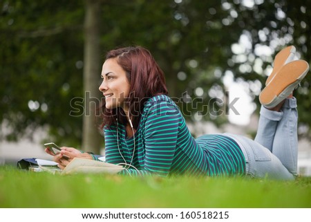 Smiling casual student lying on grass looking away on campus at college