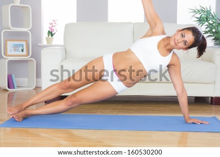 Peaceful sporty woman practicing yoga pose on blue exercise mat in her living room