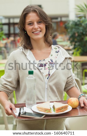 Portrait of a female student carrying food tray in the cafeteria