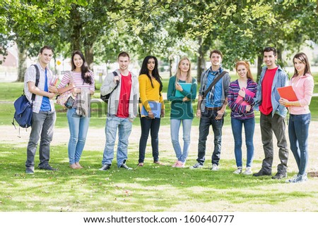 Group portrait of young college students with bags and books standing in the park