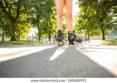 Close up of woman wearing inline skates standing on pathway in a park