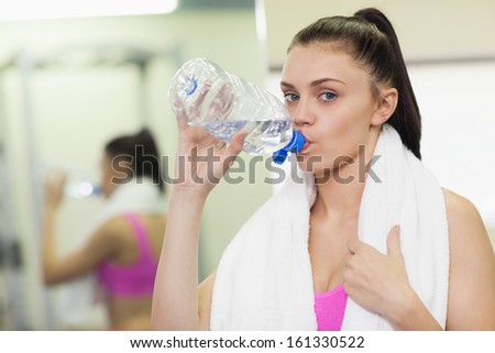 Close up portrait of a young woman drinking water in the gym