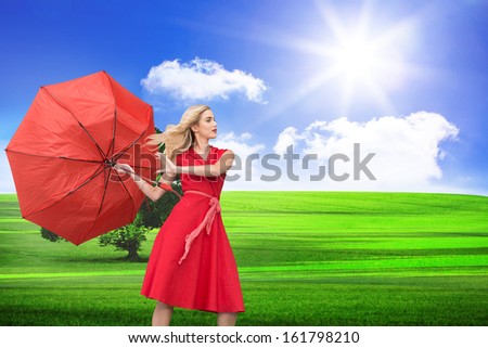 Composite image of beautiful woman posing with a broken umbrella with her leg raised