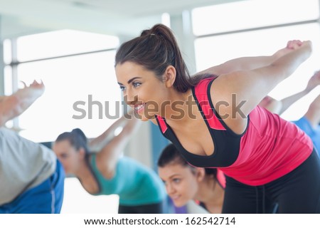 Smiling people doing power fitness exercise at yoga class in fitness studio