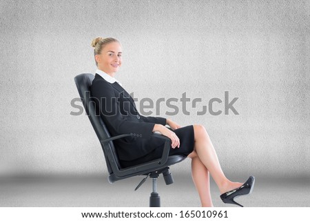 Composite image of blonde businesswoman sitting on swivel chair in black suit