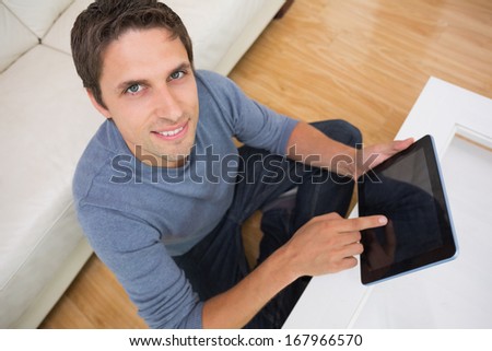 Overhead portrait of a young man using digital tablet in living room at home