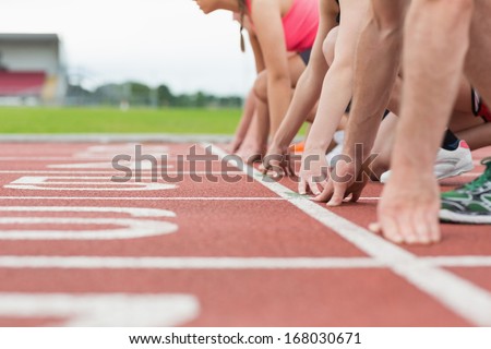Close-up side view of cropped people ready to race on track field